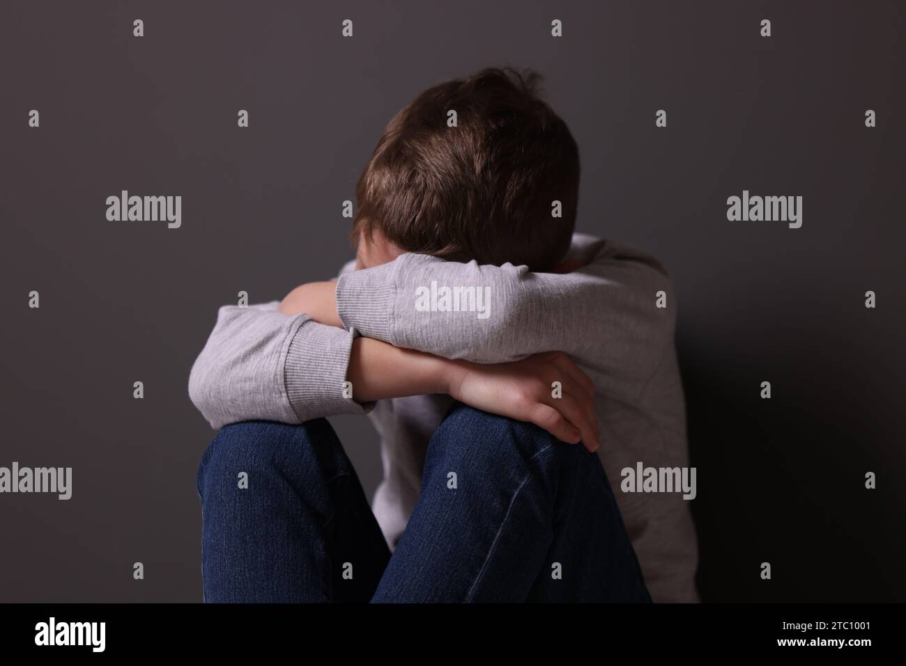 Kindesmisshandlung. Verärgerter Junge in der Nähe der grauen Wand Stockfoto