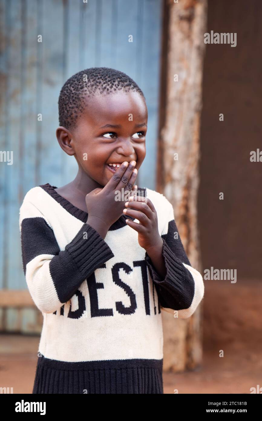 afrikanisches Dorfkind, Emotionen, Staunen und Spaß, Geste mit der Hand auf dem Mund Stockfoto