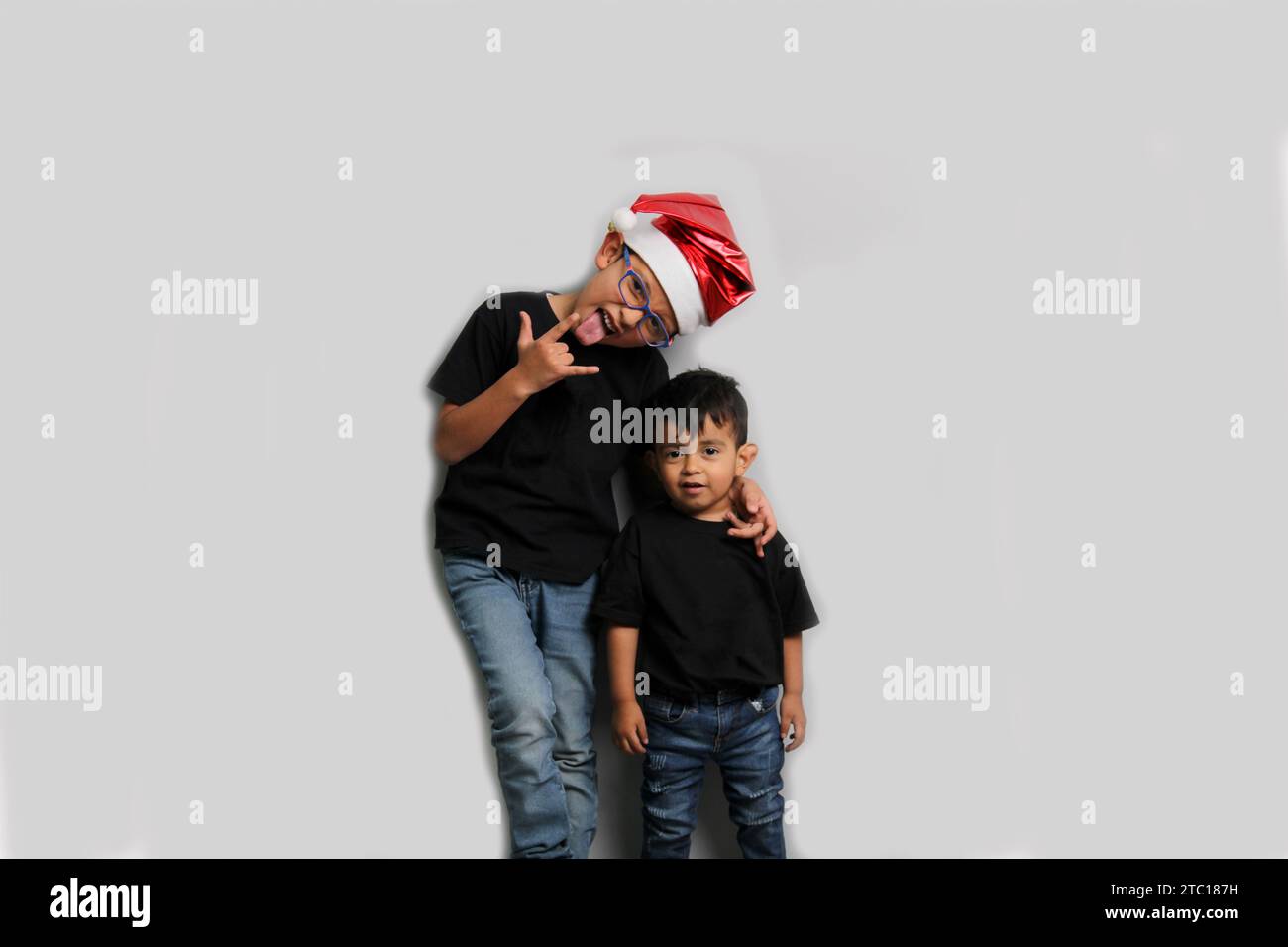 Dunkelhäutige Latino-Kinder, älterer Bruder mit Weihnachtsmütze kümmert sich um seinen jüngeren Bruder und verbringt gute Zeit an den Feiertagen, um zu feiern Stockfoto