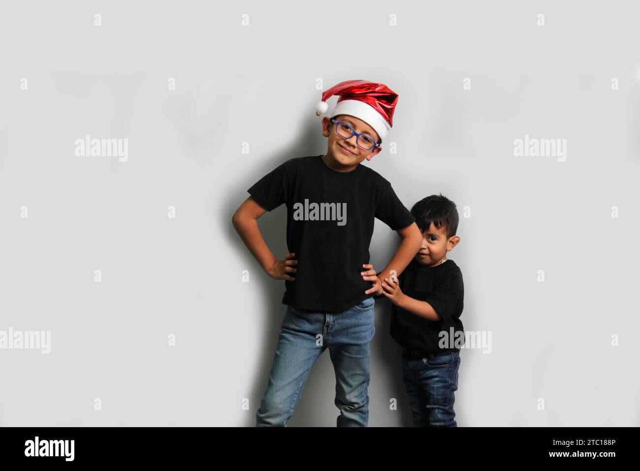 Dunkelhäutige Latino-Kinder, älterer Bruder mit Weihnachtsmütze kümmert sich um seinen jüngeren Bruder und verbringt gute Zeit an den Feiertagen, um zu feiern Stockfoto