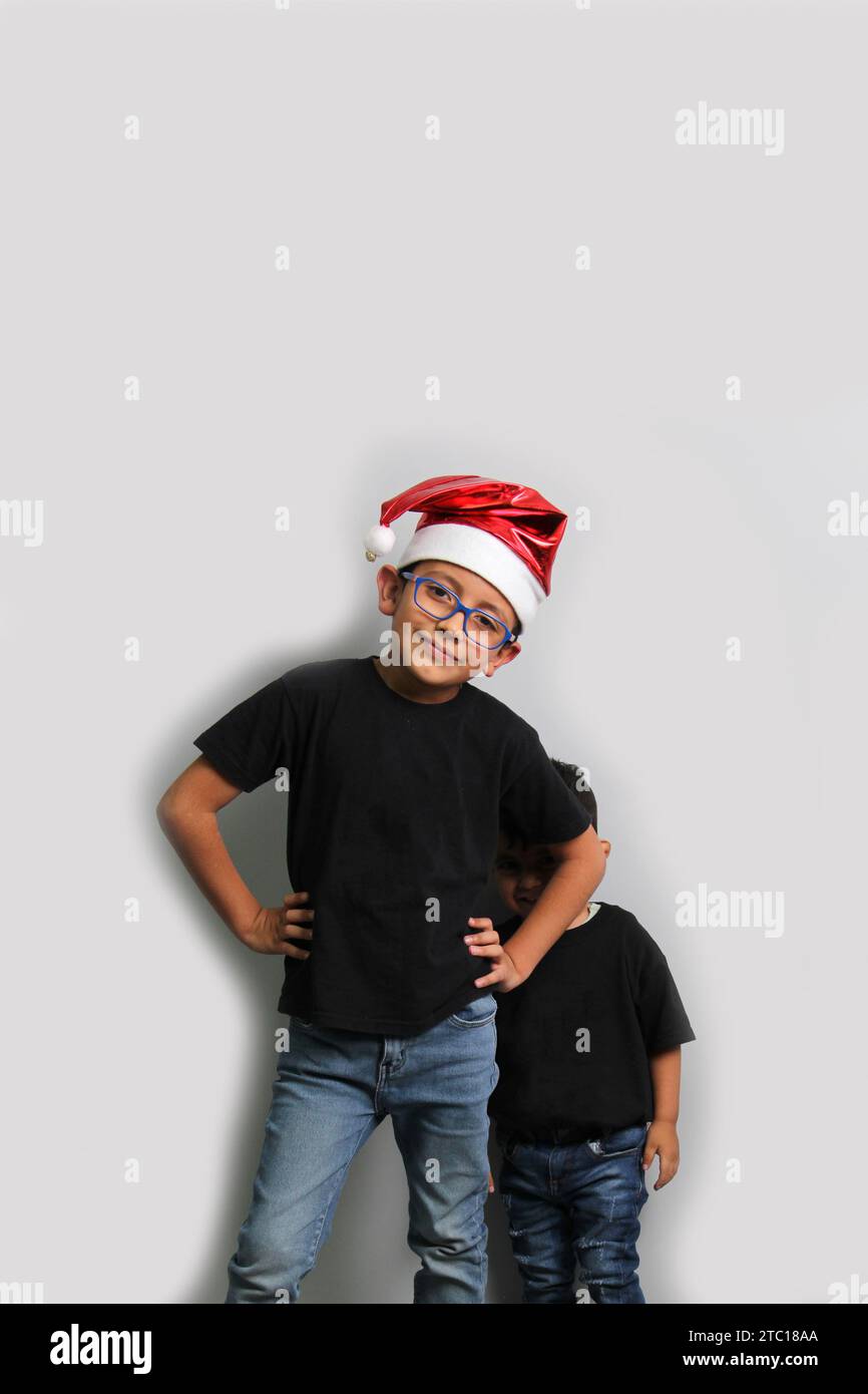 Dunkelhäutige Latino-Kinder, älterer Bruder mit Weihnachtsmütze kümmert sich um seinen jüngeren Bruder und verbringt gute Zeit an den Feiertagen, um zu feiern Stockfoto