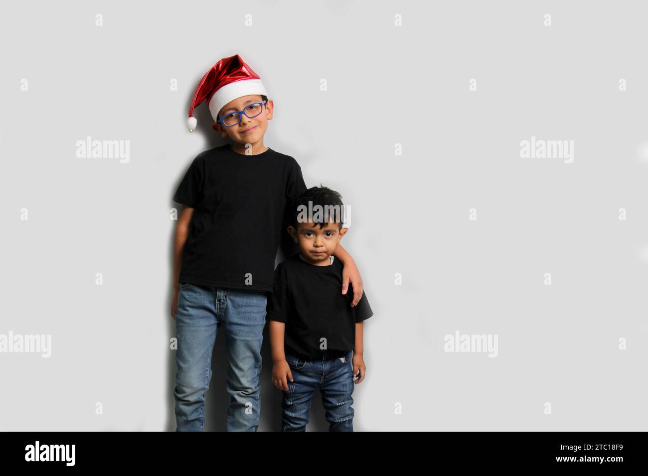 Dunkelhäutige Latino-Kinder, älterer Bruder mit Weihnachtsmütze kümmert sich um seinen jüngeren Bruder und verbringt gute Zeit an den Feiertagen, um zu feiern Stockfoto