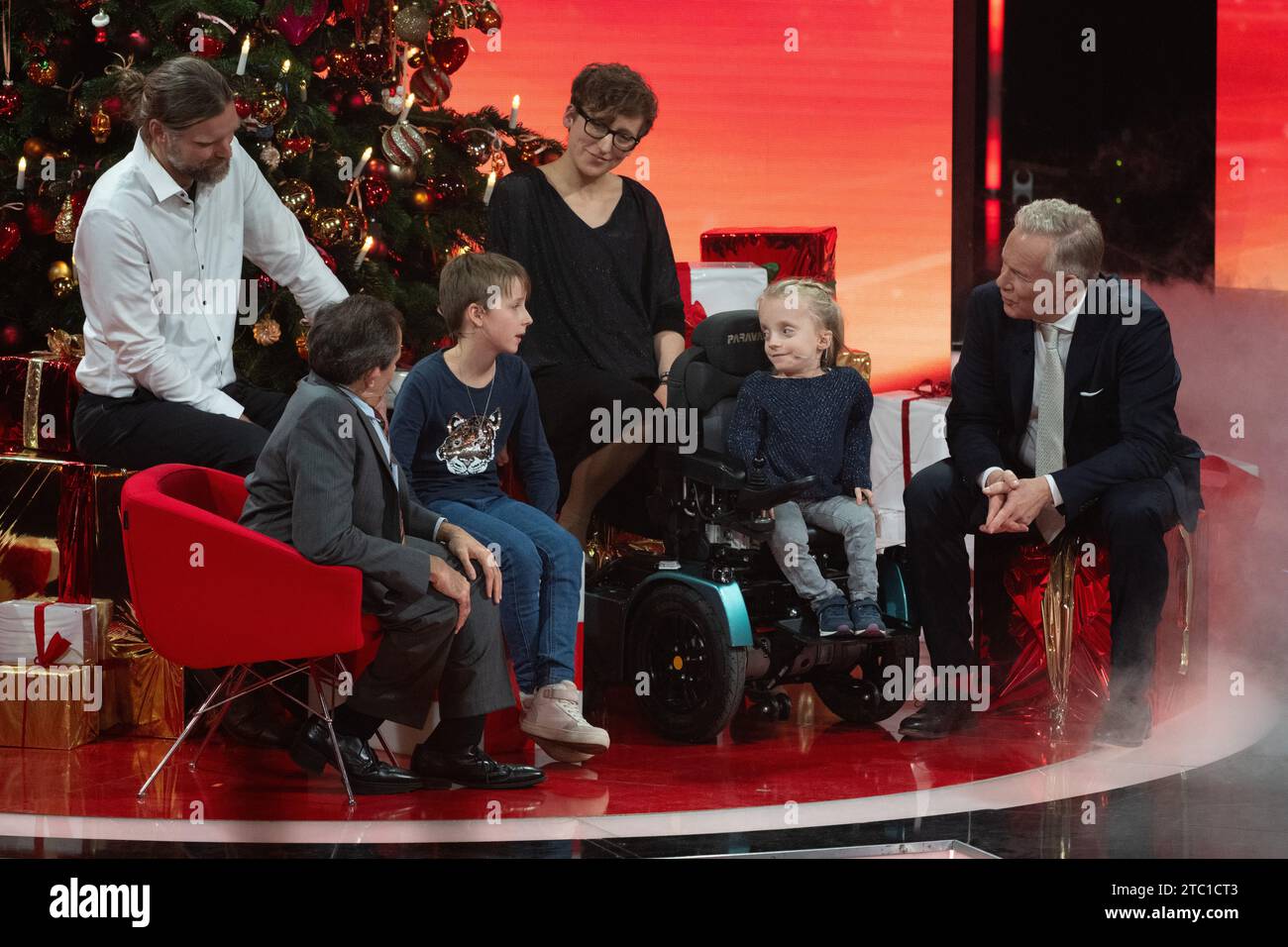 Berlin, Deutschland. Dezember 2023. Moderator Johannes B. Kerner (r-l) spricht mit der zehnjährigen Klara, WHO leidet an brüchiger Knochenerkrankung, ihre Zwillingsschwester Ronja, ihre Eltern Katrin und Roland sowie Oliver Semler, Leiter des Zentrums für seltene Skeletterkrankungen bei Kindern und Jugendlichen an der Universität zu Köln, während der TV-Spendengala „Herz für Kinder“. Quelle: Sebastian Christoph Gollnow/dpa/Alamy Live News Stockfoto