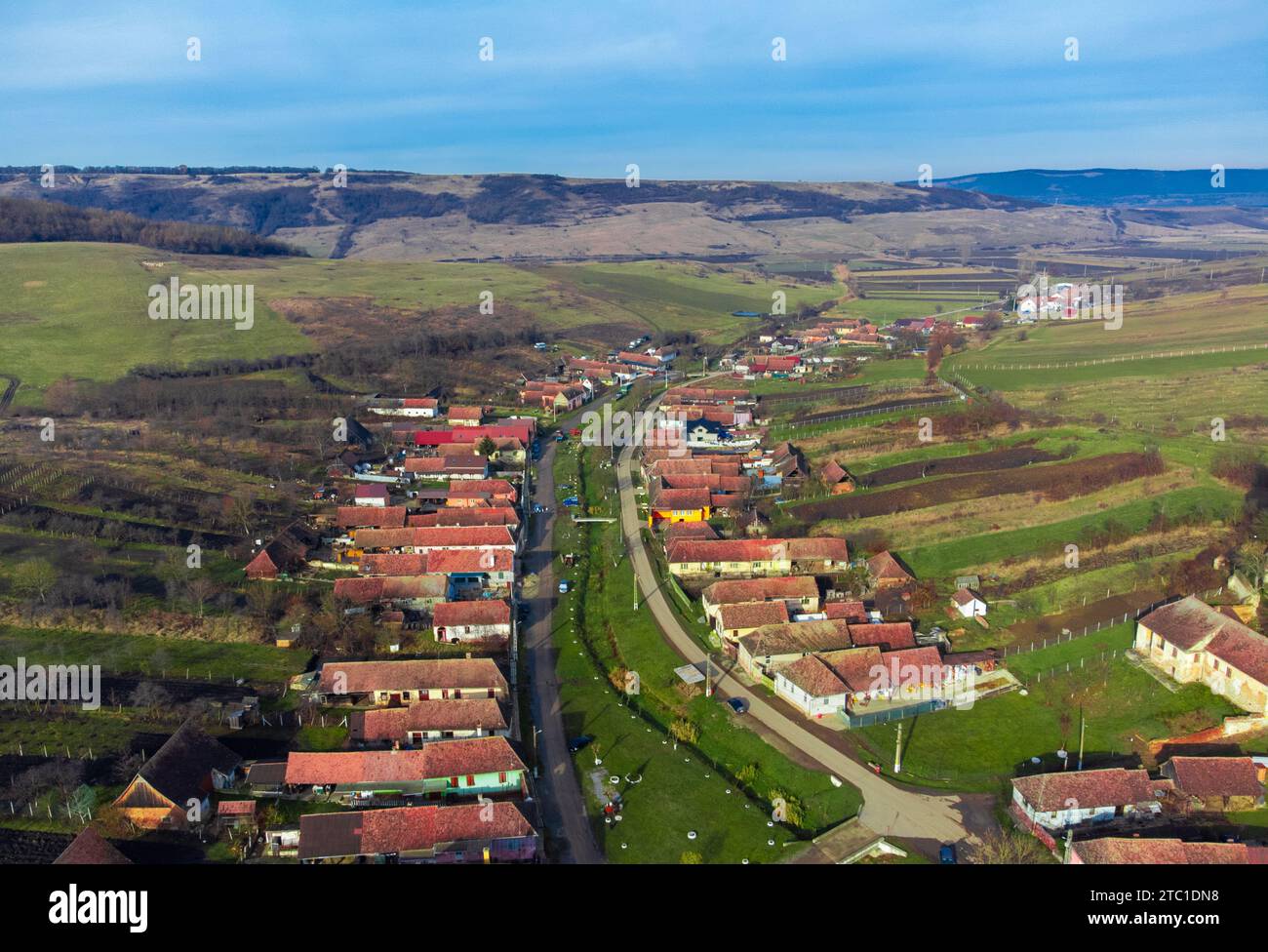 Ein Blick aus der Vogelperspektive auf ein malerisches Dorf in Rumänien, umgeben von üppigen grünen Hügeln. Stockfoto