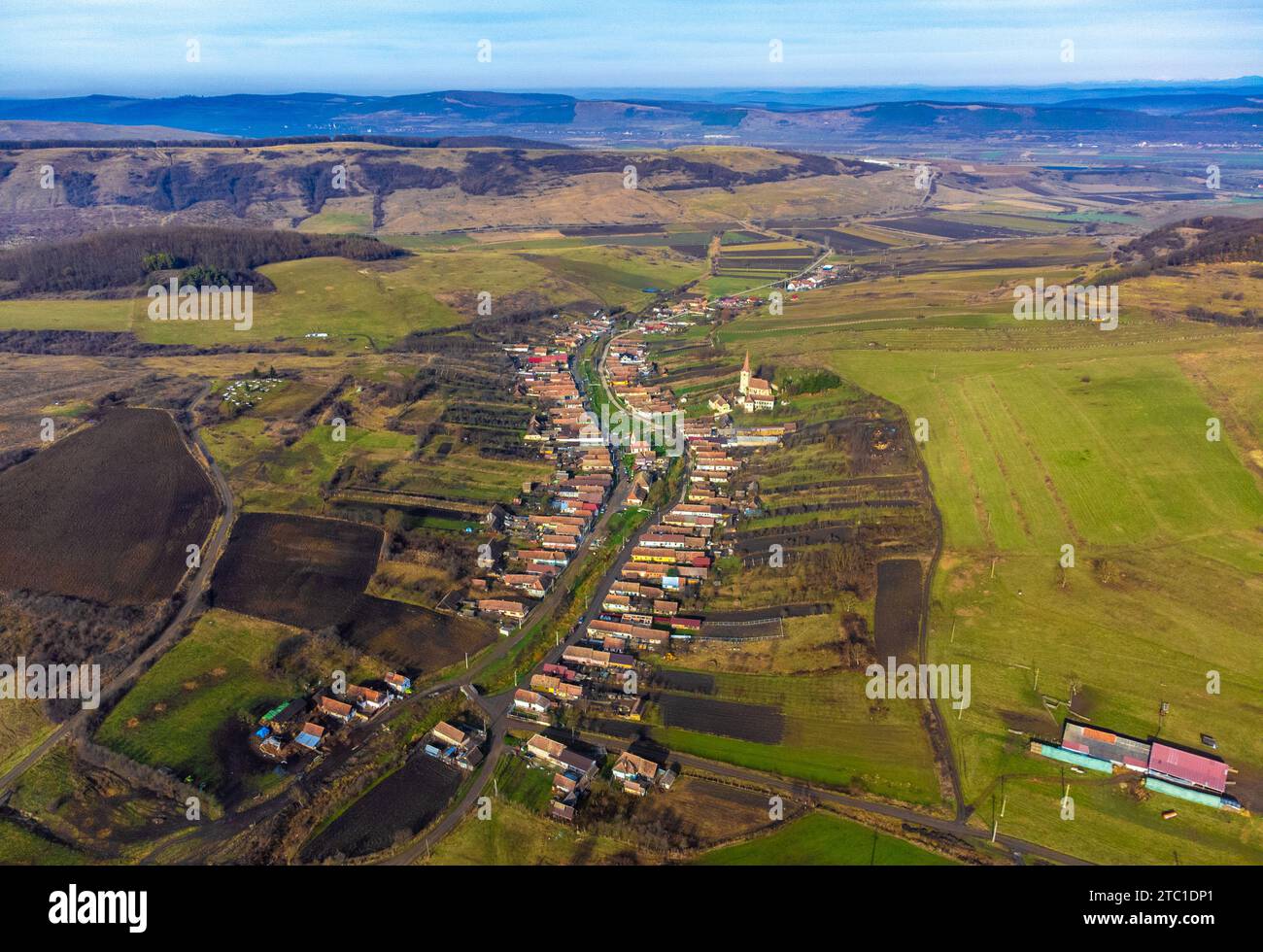 Ein Blick aus der Vogelperspektive auf ein malerisches Dorf in Rumänien, umgeben von üppigen grünen Hügeln. Stockfoto