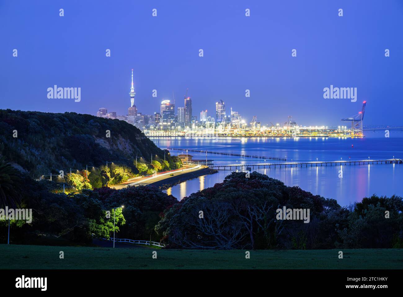Auckland Sky Tower und Skyline bei Sonnenaufgang. Lichtspuren auf der Straße im Vordergrund. Auckland. Stockfoto