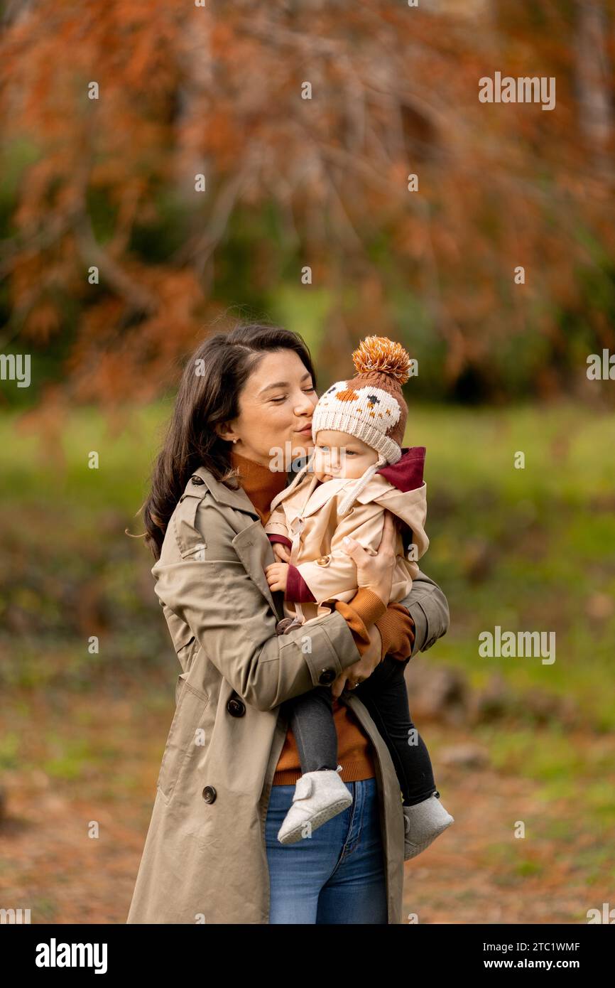 Eine junge Frau, die ein süßes Mädchen im Herbstpark hält Stockfoto