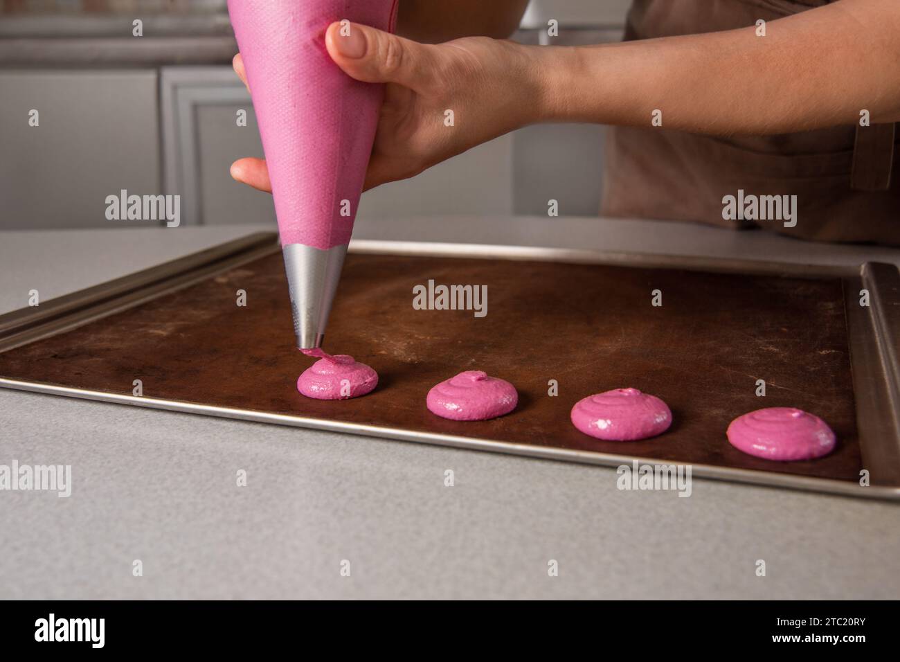 Pfeife Makronen im Kreis auf Pergamentpapier. Frau macht Macaron zu Hause Stockfoto