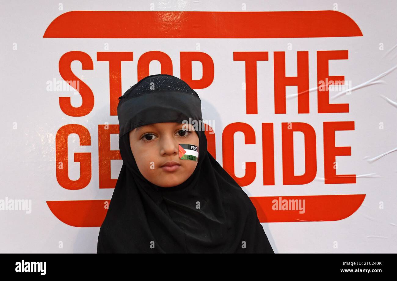 Mumbai, Indien. Dezember 2023. Ein muslimisches Mädchen steht während der Demonstration vor einem Plakat mit dem Titel "Stop the Genocide". Mehr als tausend muslimische Männer, Frauen und Kinder versammelten sich, um ihre Solidarität mit Palästina zu demonstrieren, hielten Plakate und saßen auf dem Boden, ohne irgendwelche Slogans zu schreien. Quelle: SOPA Images Limited/Alamy Live News Stockfoto