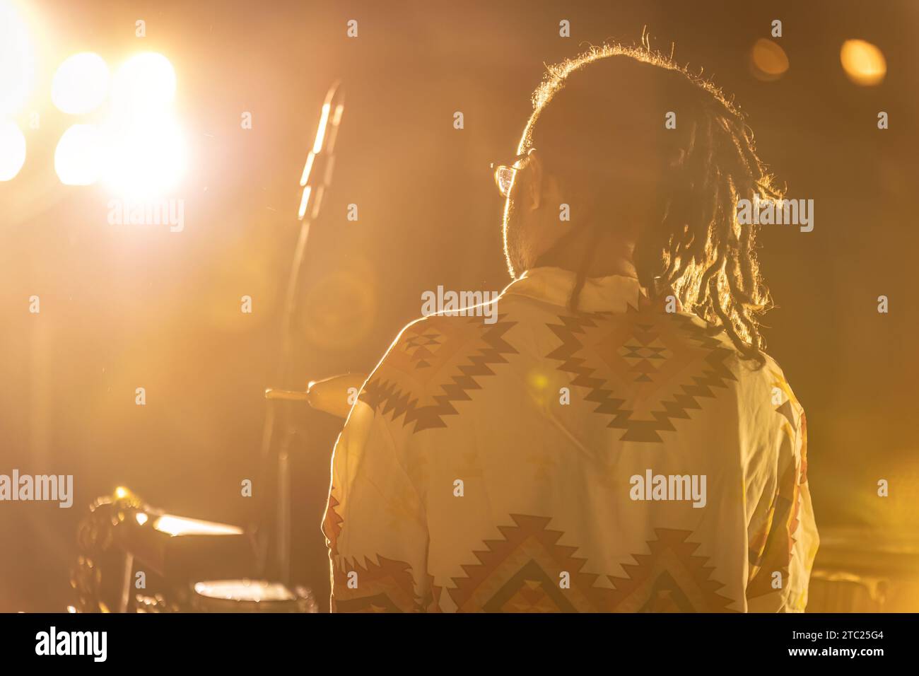 Ein Stammes-Drummer, der in Auftritte eingetaucht ist, umgeben von Nebel bei einem Nachtkonzert. Stockfoto