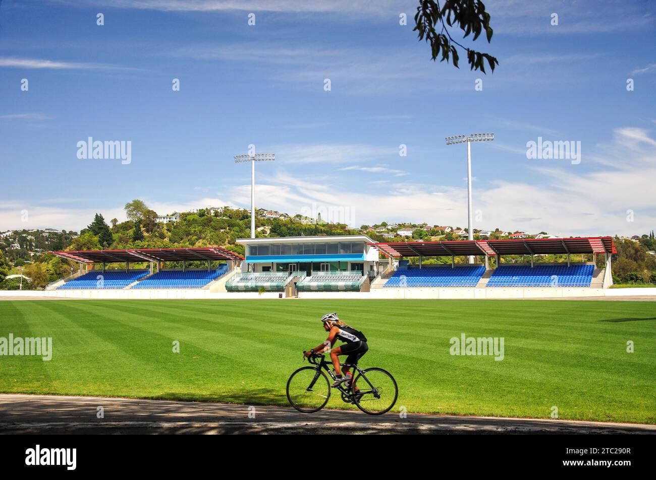 Radfahrerin auf der Strecke & Trafalgar Pavilion Building, Trafalgar Park Rugby Ground, Trafalgar Street, Nelson, Nelson Region, South Island, Neuseeland Stockfoto