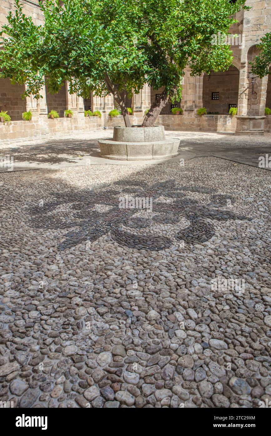 Alcantara, Spanien - 6. Oktober 2022: Gotischer Klosterkloster von San Benito de Alcantara, Caceres, Spanien. Alcantara-Kreuz auf Kieselsteinpflaster Stockfoto