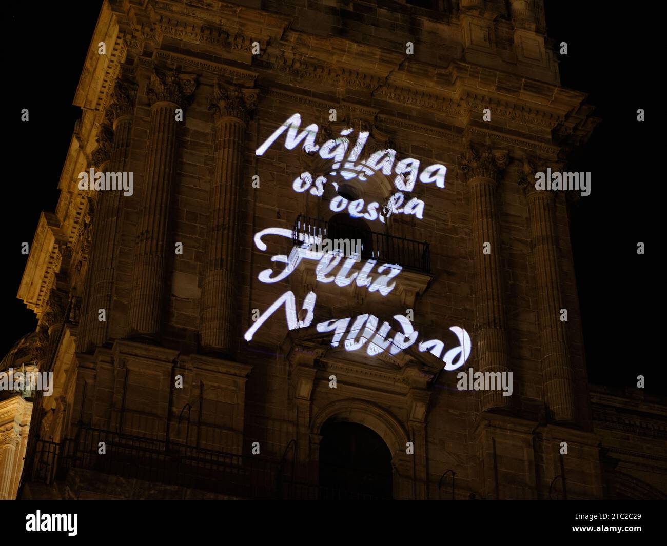 Video-Mapping-Show auf der Kathedrale von Malaga mit einem Text auf Spanisch, in dem steht, dass Malaga Ihnen frohe Weihnachten wünscht. Stockfoto