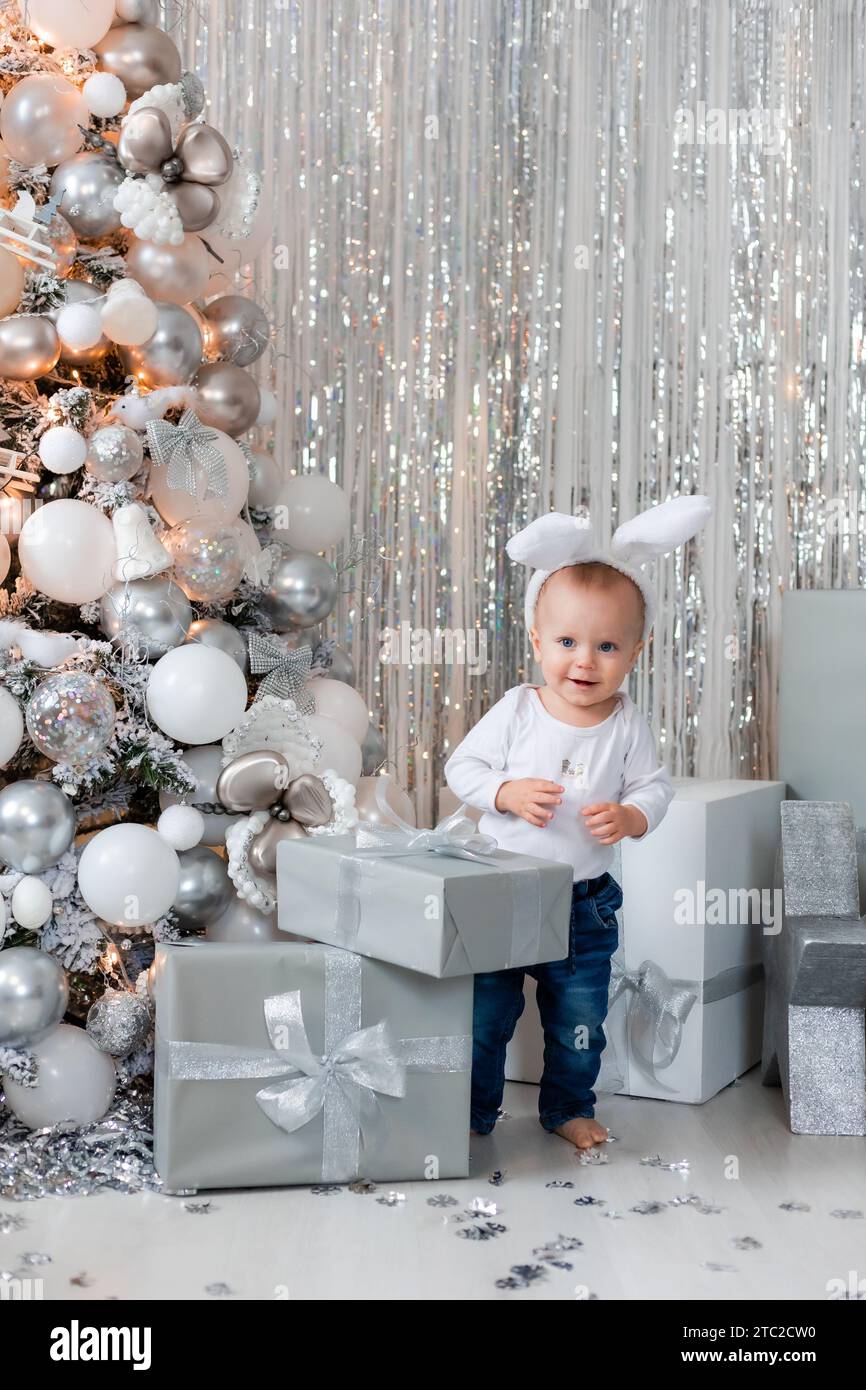 Süßer Junge mit Geschenken am Weihnachtsbaum, kleiner Weihnachtsmann Stockfoto