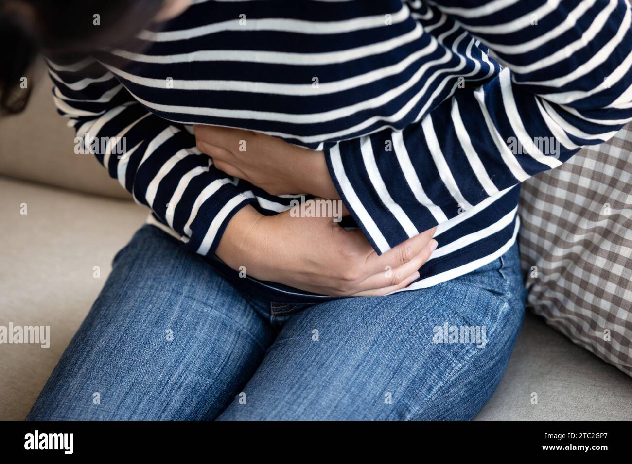 Junge Frau, die zu Hause unter Magenschmerzen leidet, Nahaufnahme. Lebensmittelvergiftung, Krämpfe Stockfoto