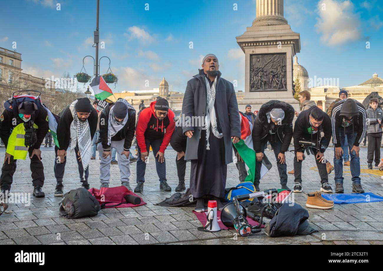 London / UK - 9. Dezember 2023: Eine Gruppe muslimischer Männer betet auf dem Trafalgar Square bei einer pro-palästinensischen Demonstration, die ein Ende der israelischen Angriffe auf G fordert Stockfoto