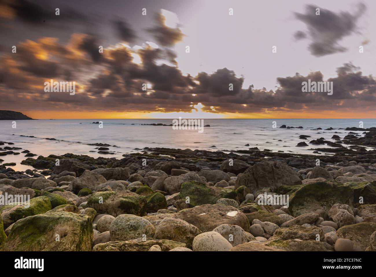 Lebendiger Sonnenuntergang über dem Horizont des Ozeans mit einer felsigen Küste in Sao Martinho do Porto, Portugal Stockfoto