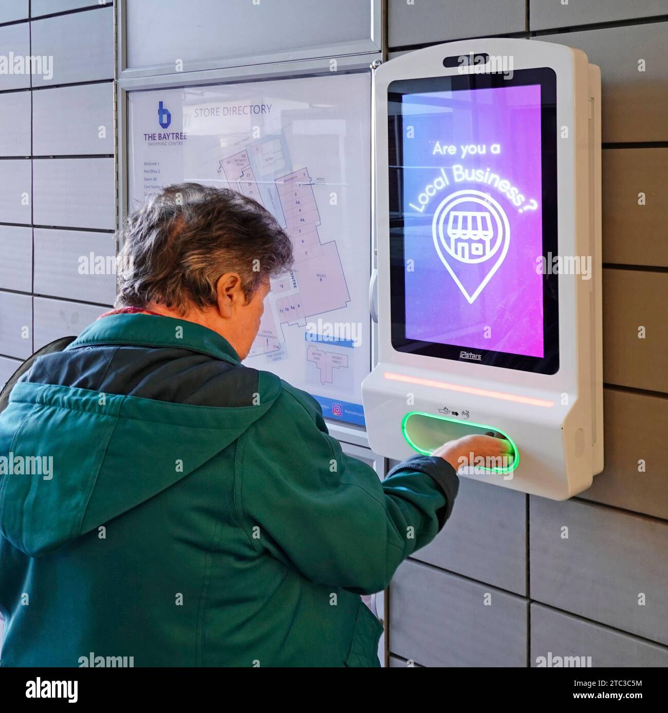 Ältere reife Frau Rückansicht steckt eine Hand in Schlitz an der Wand montierte automatische Desinfektionsgel Dispenser Bildschirm zeigt Werbung Einkaufszentrum Essex England Großbritannien Stockfoto Ältere reife Frau Rückansicht steckt eine Hand in Schlitz an der Wand montierte automatische Desinfektionsgel Dispenser Bildschirm zeigt Werbung Einkaufszentrum Essex England Großbritannien Stockfoto
