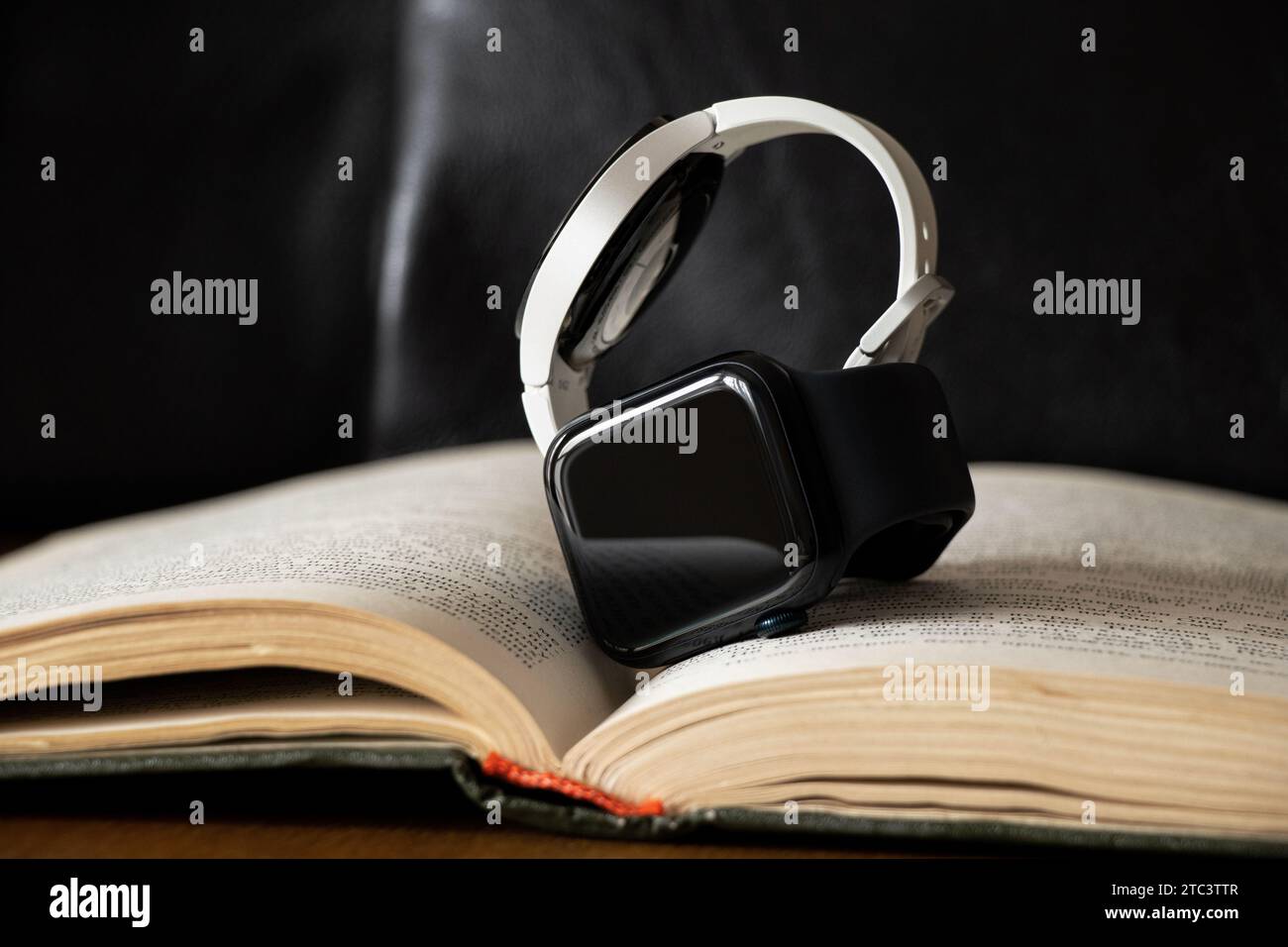 Dnipro, Ukraine - 10. Dezember 2023: Weiße Smart Uhren Samsung Galaxy Active und Apple Watch Series 8 liegen auf dem Tisch zu Hause auf einem Buch, zwei Smart Stockfoto