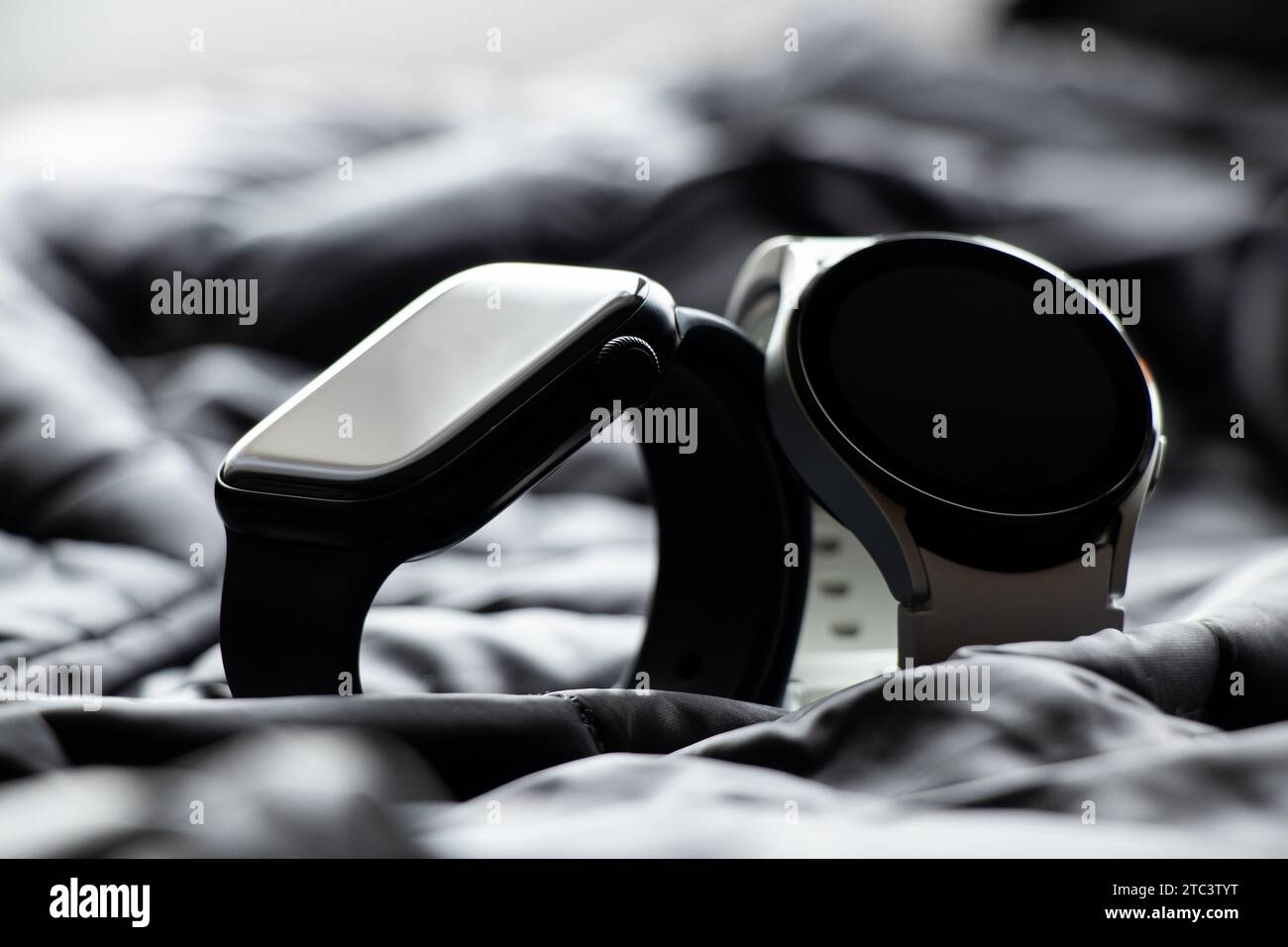 Dnipro, Ukraine - 10. Dezember 2023: Smart Watches Samsung Galaxy Active Watch weiß und Apple Watch Series 8 schwarz liegen auf einem grauen Stoff, Smart Watche Stockfoto