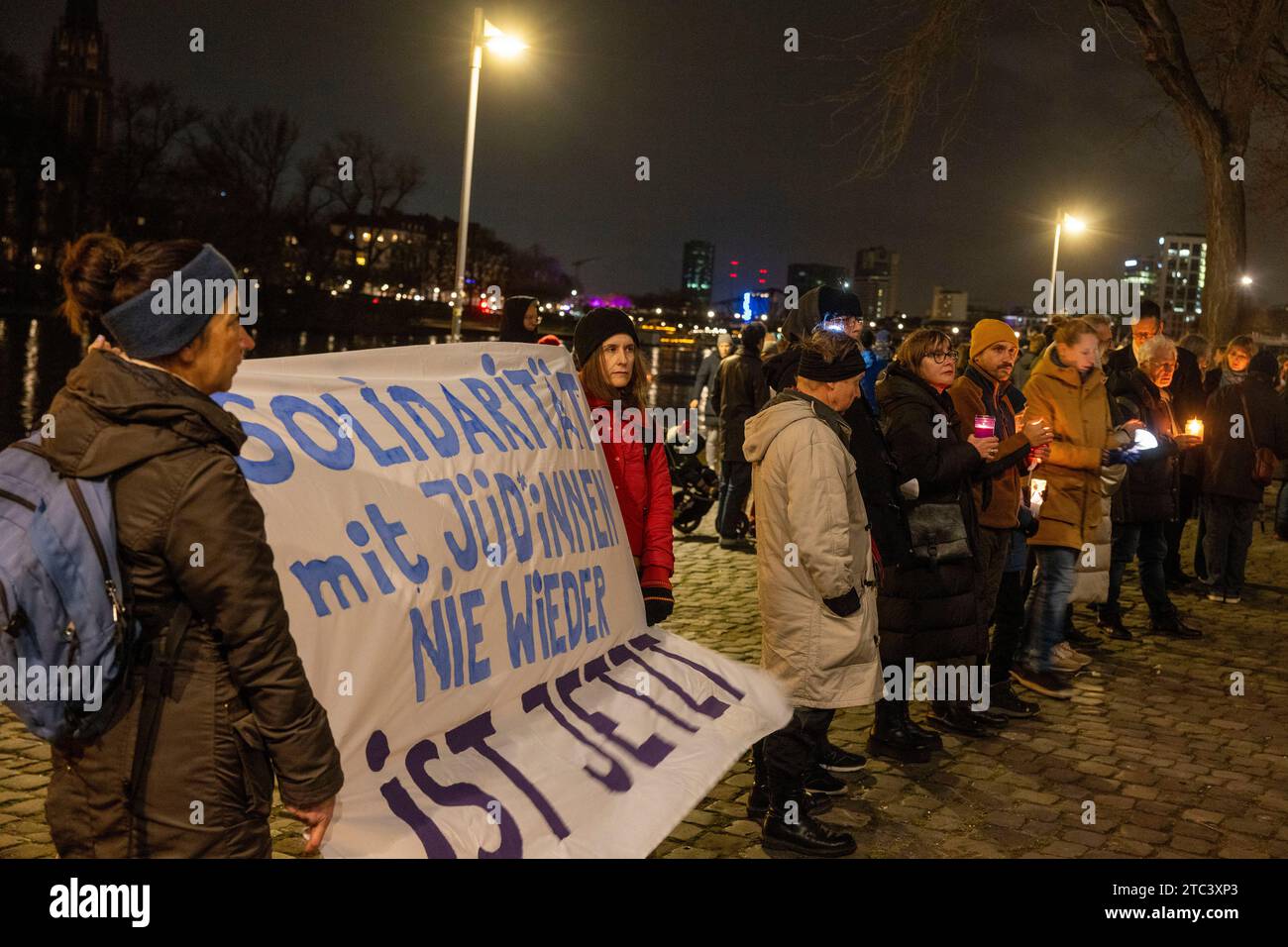 10. Dezember 2023, Hessen, Frankfurt/Main: Menschen nehmen an einer Lichterkette gegen Antisemitismus Teil. Frankfurts Kulturführer fordern eine Lichterkette entlang des Mainufers. Die katholische Rabanus-Maurus-Akademie, die Evangelische Akademie und zahlreiche andere kulturelle Einrichtungen der Stadt gehören zu den Sponsoren der Kampagne. Foto: Helmut Fricke/dpa Stockfoto