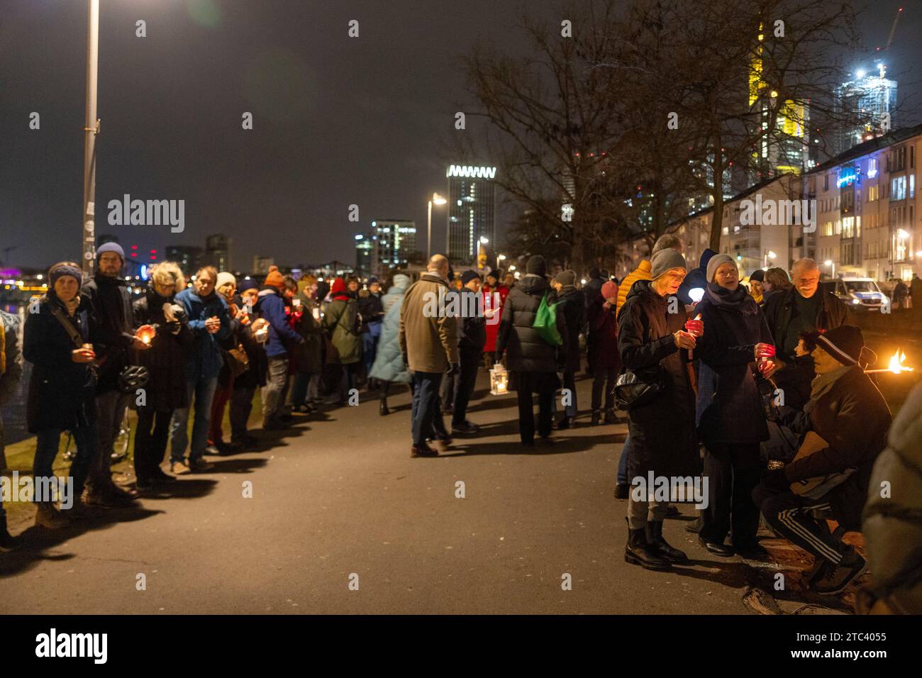 10. Dezember 2023, Hessen, Frankfurt/Main: Menschen nehmen an einer Lichterkette gegen Antisemitismus Teil. Frankfurts Kulturführer fordern eine Lichterkette entlang des Mainufers. Die katholische Rabanus-Maurus-Akademie, die Evangelische Akademie und zahlreiche andere kulturelle Einrichtungen der Stadt gehören zu den Sponsoren der Kampagne. Foto: Helmut Fricke/dpa Stockfoto