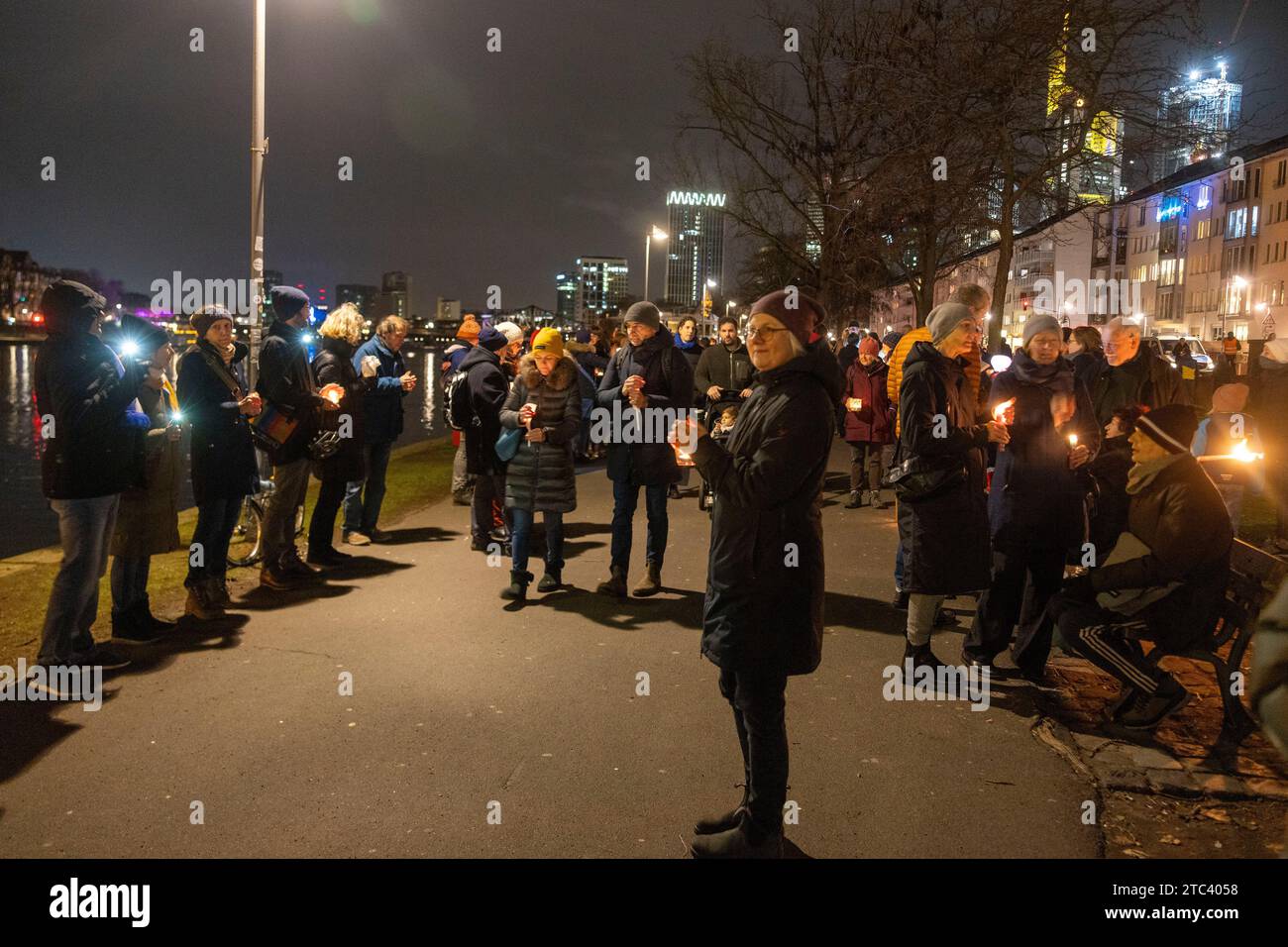 10. Dezember 2023, Hessen, Frankfurt/Main: Menschen nehmen an einer Lichterkette gegen Antisemitismus Teil. Frankfurts Kulturführer fordern eine Lichterkette entlang des Mainufers. Die katholische Rabanus-Maurus-Akademie, die Evangelische Akademie und zahlreiche andere kulturelle Einrichtungen der Stadt gehören zu den Sponsoren der Kampagne. Foto: Helmut Fricke/dpa Stockfoto