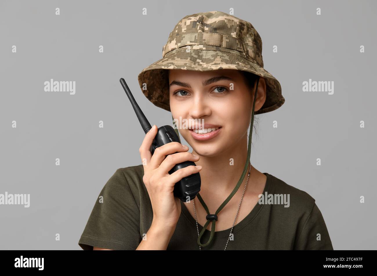 Soldatinnen in Tarnuniform, die in Militärradio auf grauem Hintergrund sprechen Stockfoto