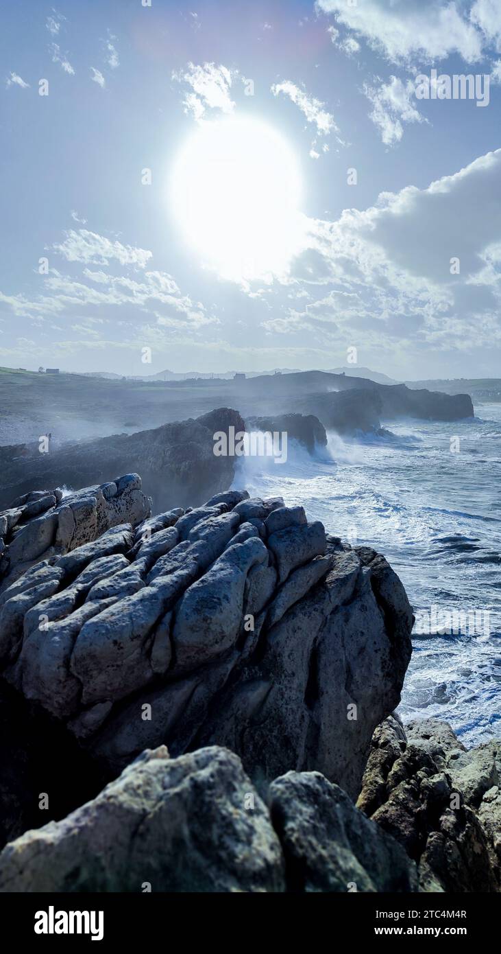 Vertikales Foto einer Klippe mit Meer und starken Wellen, die einen sonnigen Tag mit Kopierraum abrunden Stockfoto