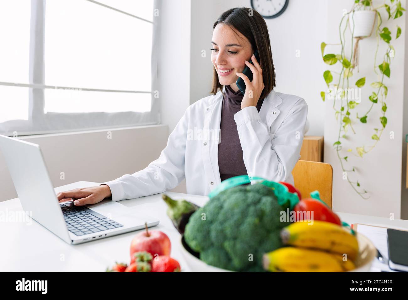 Junge lächelnde Ernährungsberaterin im Sprechzimmer Stockfoto