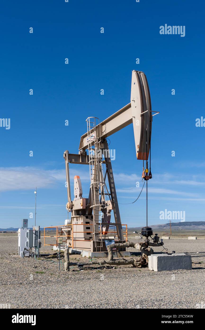 Eine funktionierende Ölpumpe hebt sich gegen den blauen Himmel an. Colorado, USA Stockfoto