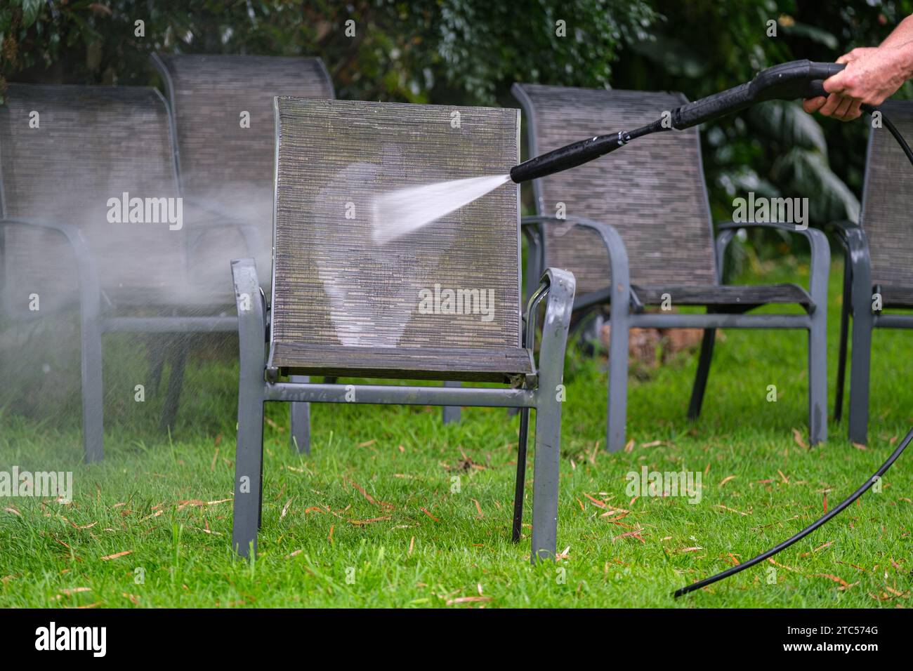 Reinigung von Außenmöbeln mit einem Wasserstrahler Stockfoto
