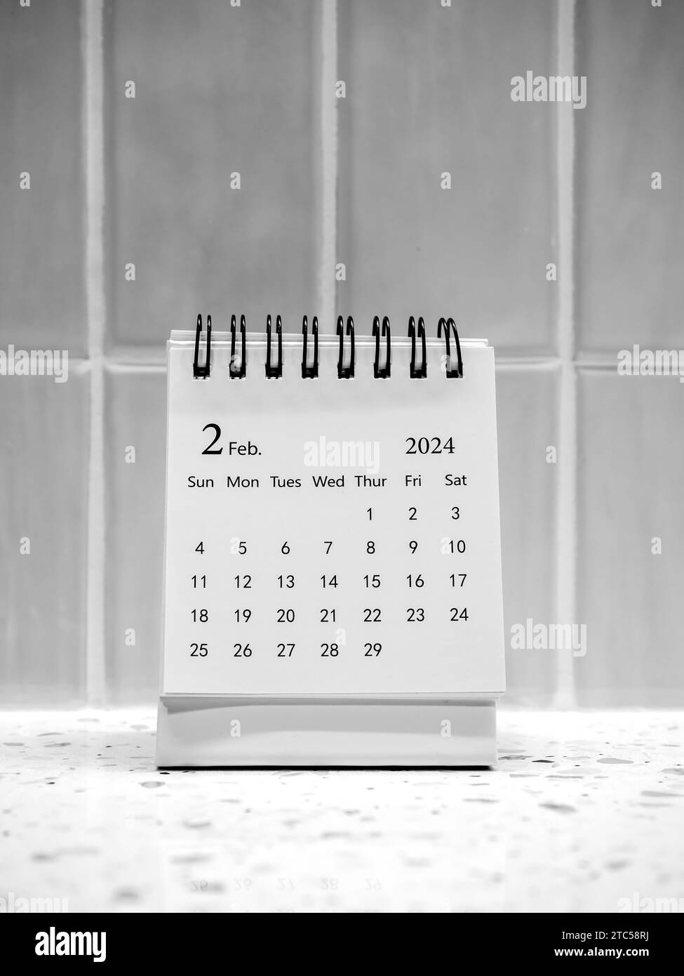 Ein Februar 2024 auf dem Kalender-Schreibtisch für Organisator, um zu planen und Erinnerungen auf vertikalen weißen Fliesen Hintergrund, minimalen Stil. Weißer kleiner Tischkalender mit Stockfoto
