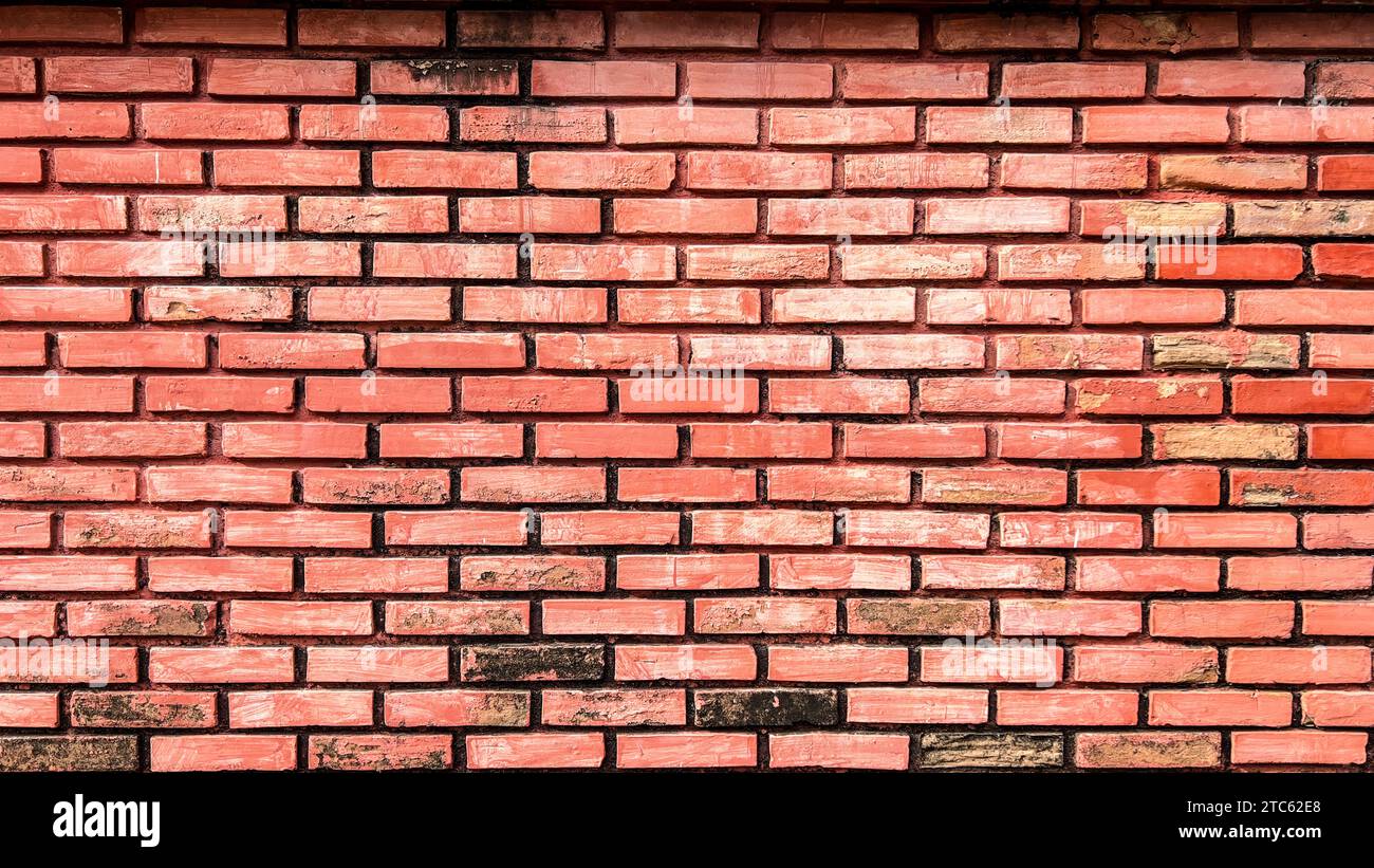 Eine Nahaufnahme einer Ziegelwand mit Anzeichen von Verschleiß, abplatzender Farbe und verblassten Farben Stockfoto