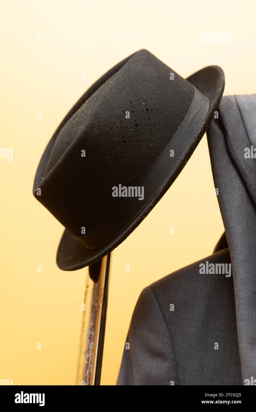 Ein eleganter schwarzer Hut auf einem Kleiderständer mit einer Auswahl an stilvollen grauen Anzügen Stockfoto