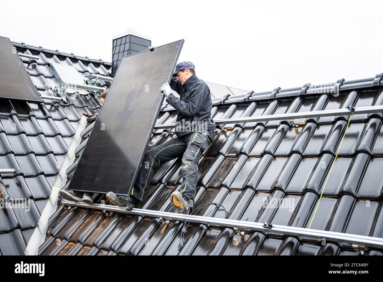 Solarmodul-Techniker, der Photovoltaikanlage auf dem Dach eines Wohnhauses installiert Stockfoto