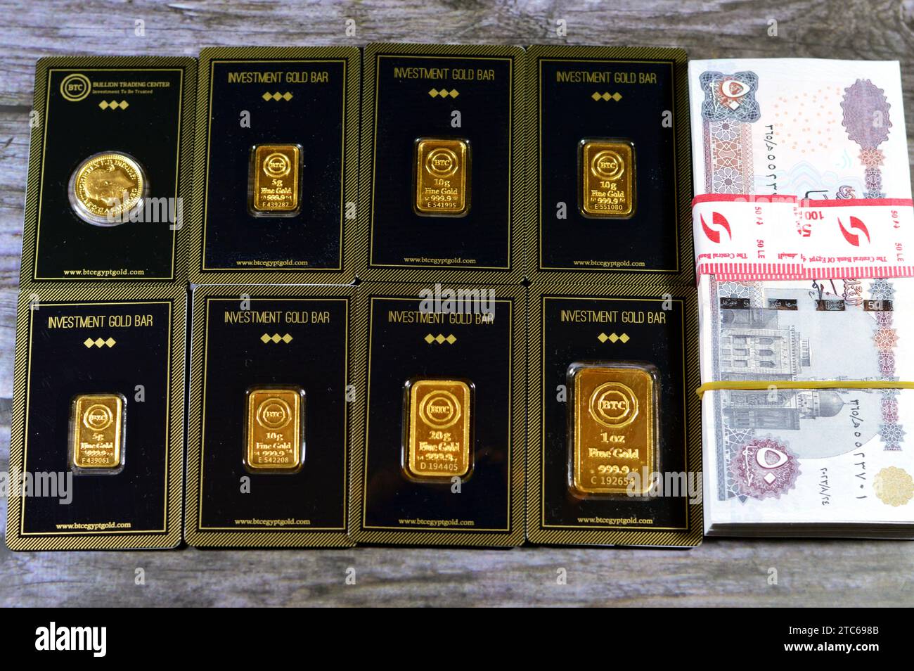 Kairo, Ägypten, 8. Dezember 2023: 24 Karat BTC Bullion Trading Center reines gelbes Gold aus Barren und souveränen Münzen und ein Stapel ägyptischer Geldbanknot Stockfoto
