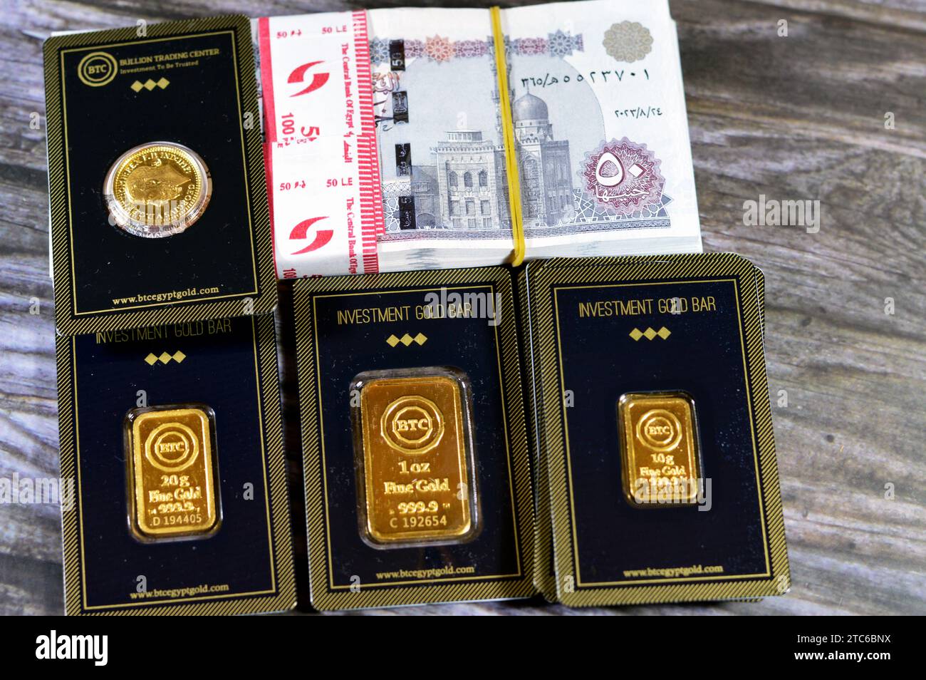 Kairo, Ägypten, 8. Dezember 2023: 24 Karat BTC Bullion Trading Center reines gelbes Gold aus Barren und souveränen Münzen und ein Stapel ägyptischer Geldbanknot Stockfoto