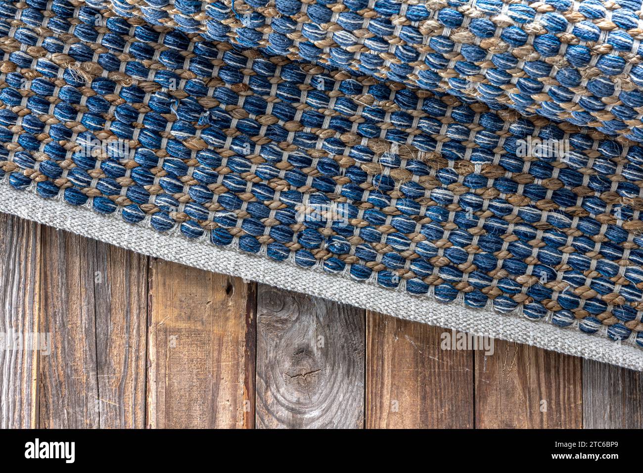 Handgewebter Teppich mit geometrischem Denim-Bereich auf Holzboden. Stockfoto