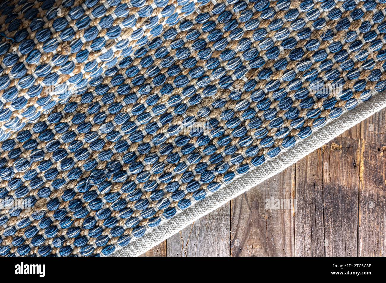 Handgewebter Teppich mit geometrischem Denim-Bereich auf Holzboden. Stockfoto