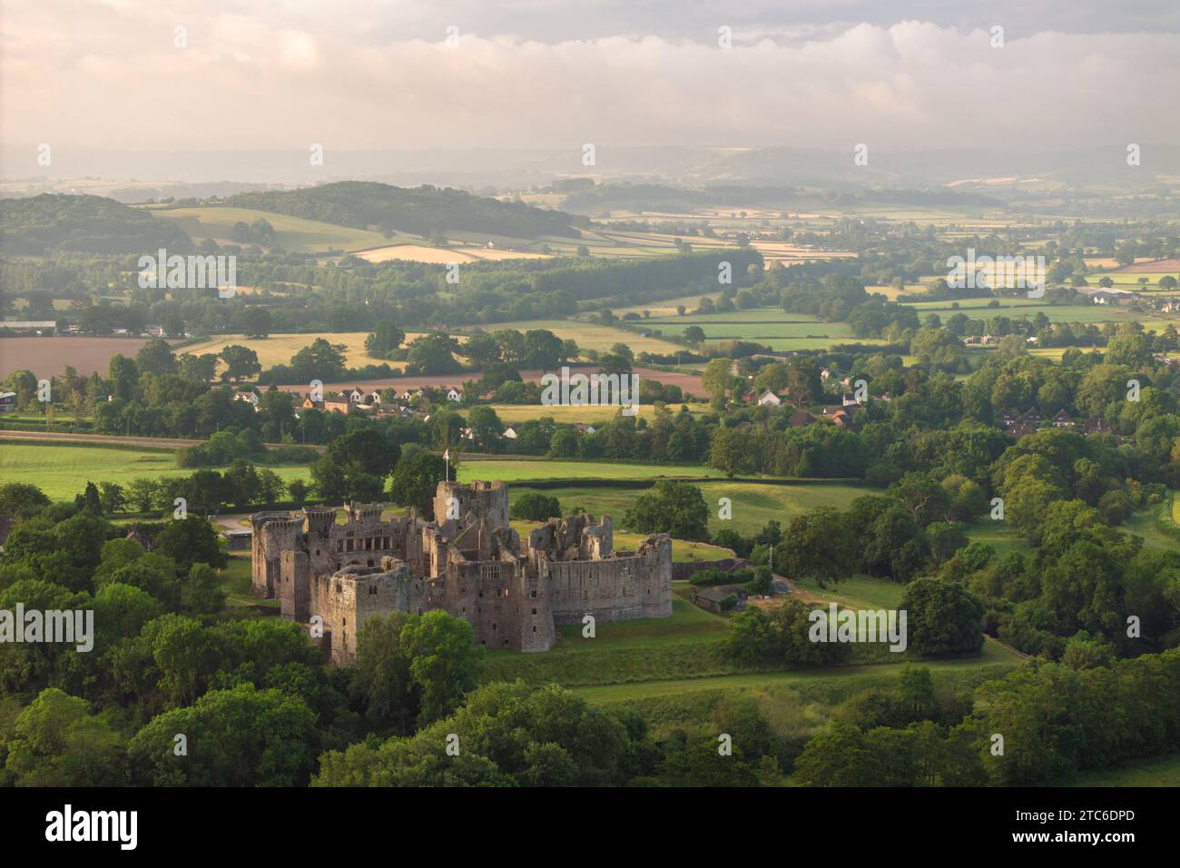 Aus der Vogelperspektive auf die Ruinen von Raglan Castle an einem nebeligen Morgen, Monmouthshire, Wales, Großbritannien. Sommer (Juni) 2023. Stockfoto