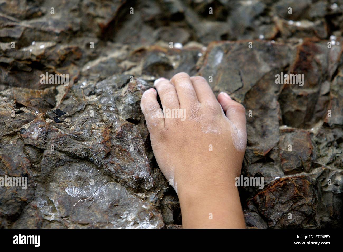 Eine Hand greift den Felsen, während sie eine Felswand in Malibu, Kalifornien, erklimmt. Stockfoto
