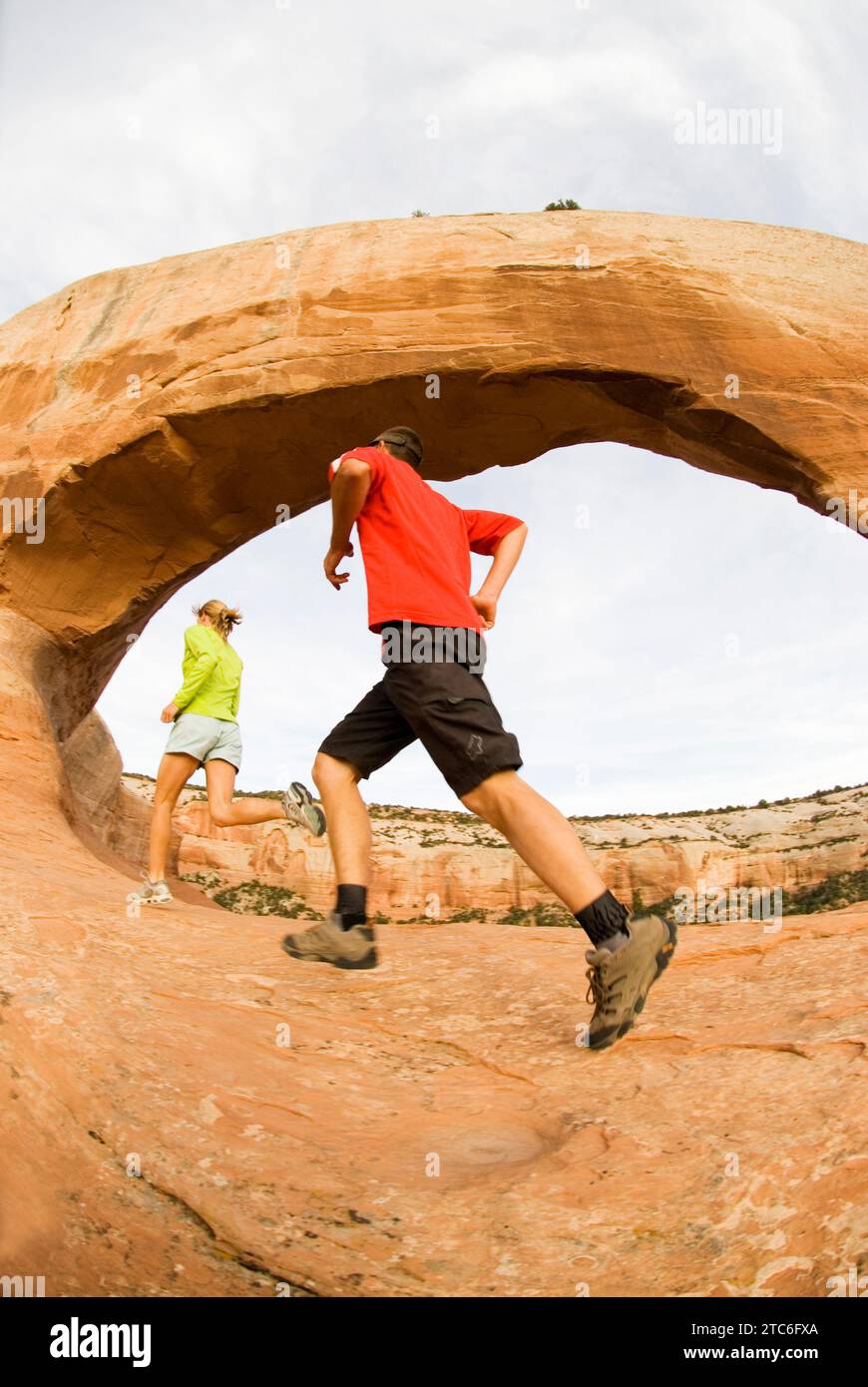 Zwei Leute laufen unter Wilson Arch in der Nähe von Moab, Utah. Stockfoto