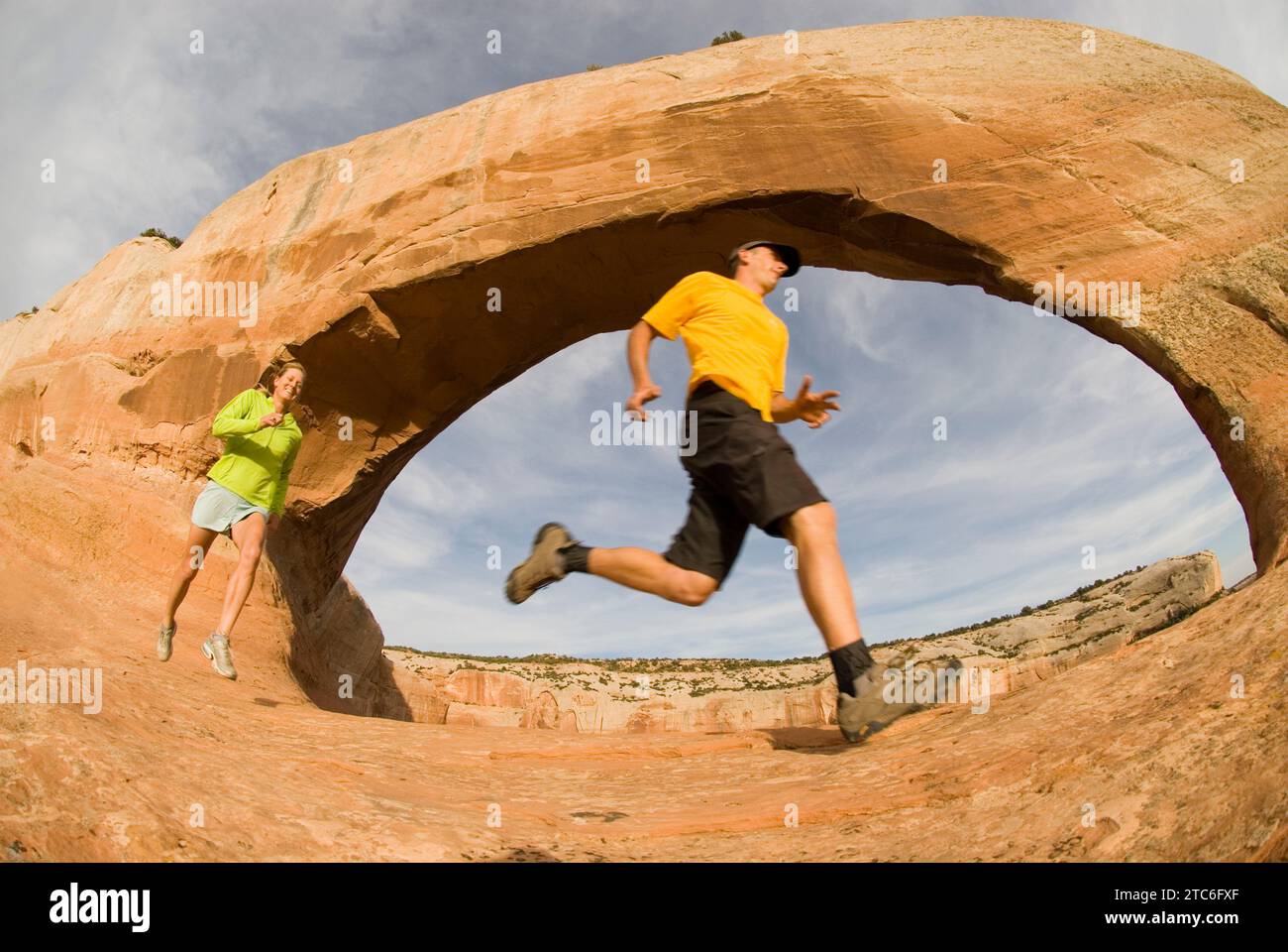 Zwei Leute laufen unter Wilson Arch, Moab, Utah. Stockfoto