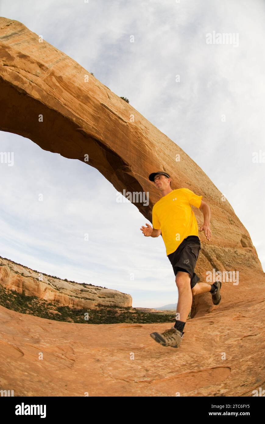 Ein Mann, der unter Wilson Arch in der Nähe von Moab, Utah, läuft. Stockfoto