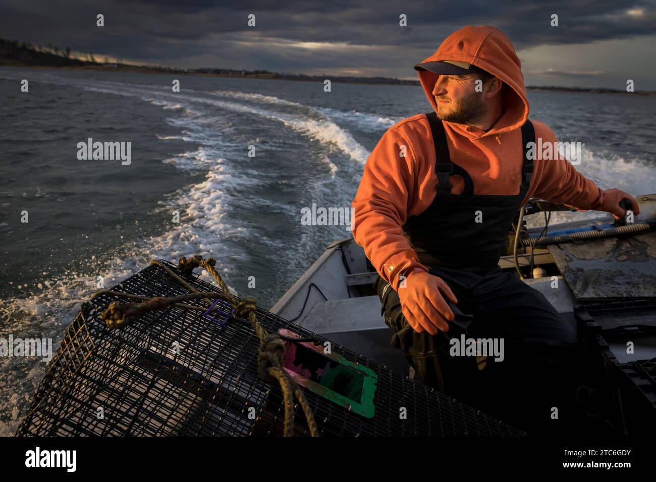 Kommerzieller Fischer, der ein Fischerboot mit stürmischem Himmel fährt Stockfoto