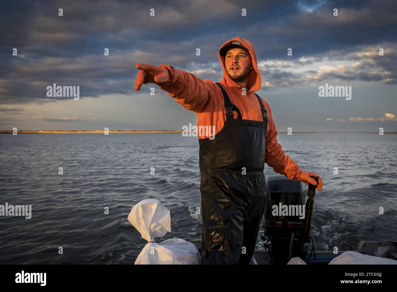 Kommerzieller Fischer im Boot, der auf etwas in der Ferne zeigt Stockfoto