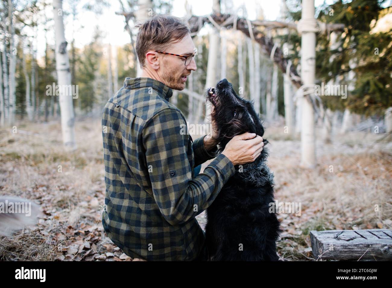 Mann, der sich mit schwarzem Hund in Stanley, Idaho Forest verbündet Stockfoto