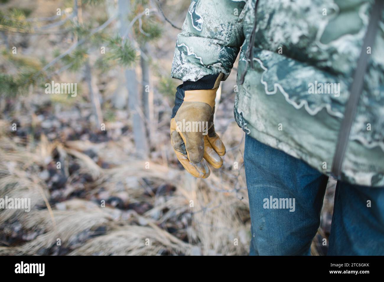Jäger in Tarnung mit Lederhandschuhen im Wald Stockfoto