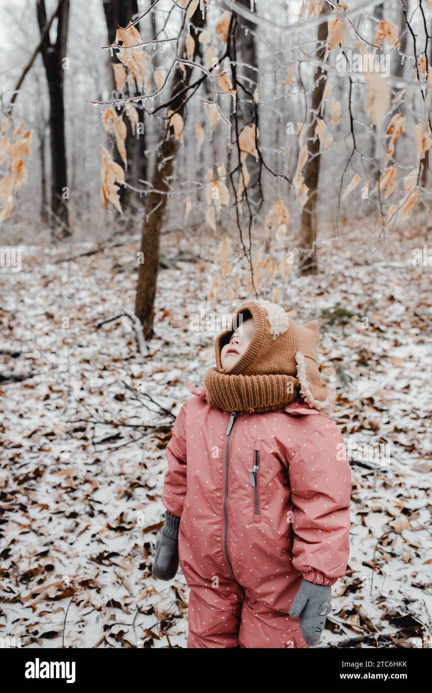 Kind im Schneesuck, das auf Eiszapfen auf Bäumen blickt Stockfoto